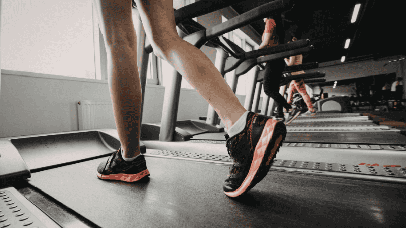 A female athlete wearing Nike Pegasus running shoes while transitioning from a treadmill interval run to a strength training workout in a gym setting.