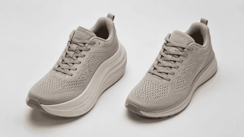 Side by side comparison of a Hoka walking shoe and a Brooks walking shoe placed next to each other on a neutral surface, showing the difference in sole thickness and heel drop between the two brands