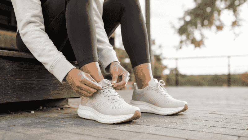 A beginner runner lacing up their first pair of running shoes before heading out for a run, showing the excitement and preparation of starting a new running journey
